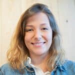 Close-up portrait of a smiling woman wearing a denim jacket with wooden background.
